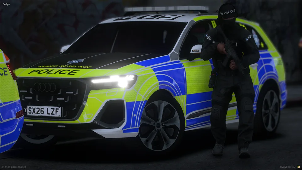 Armed Stonehaven police officer beside a marked response vehicle